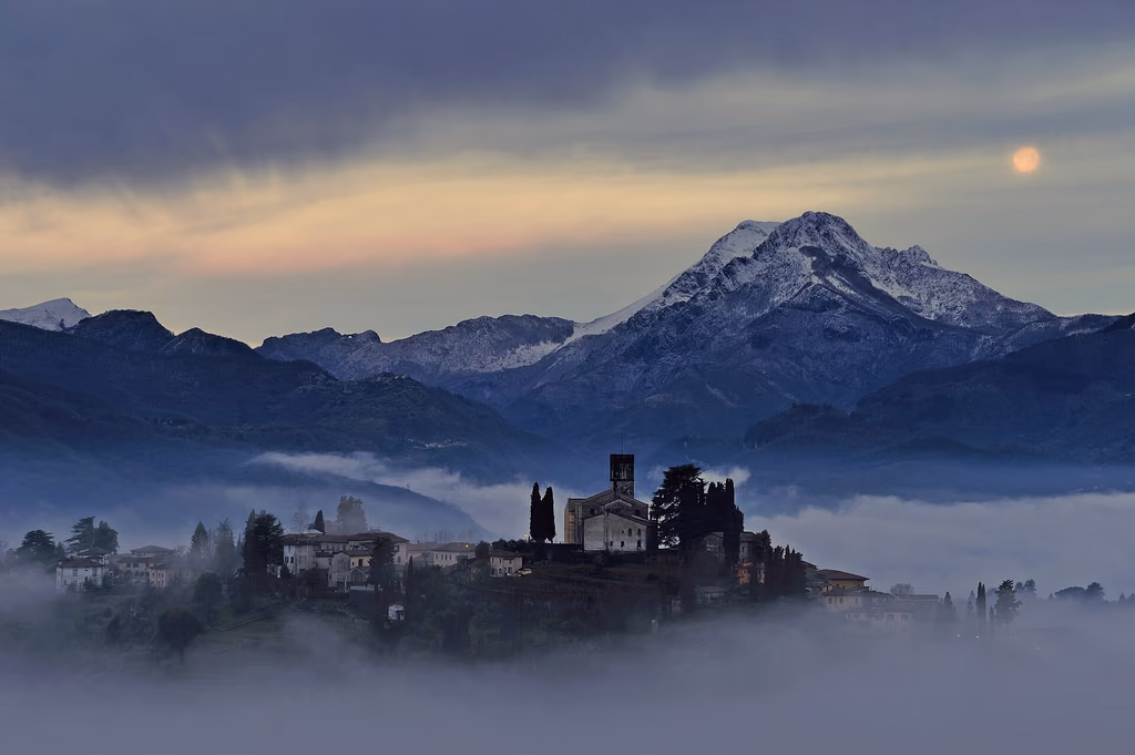 Barga and its cathedral below the Apuan Alps on a misty morning