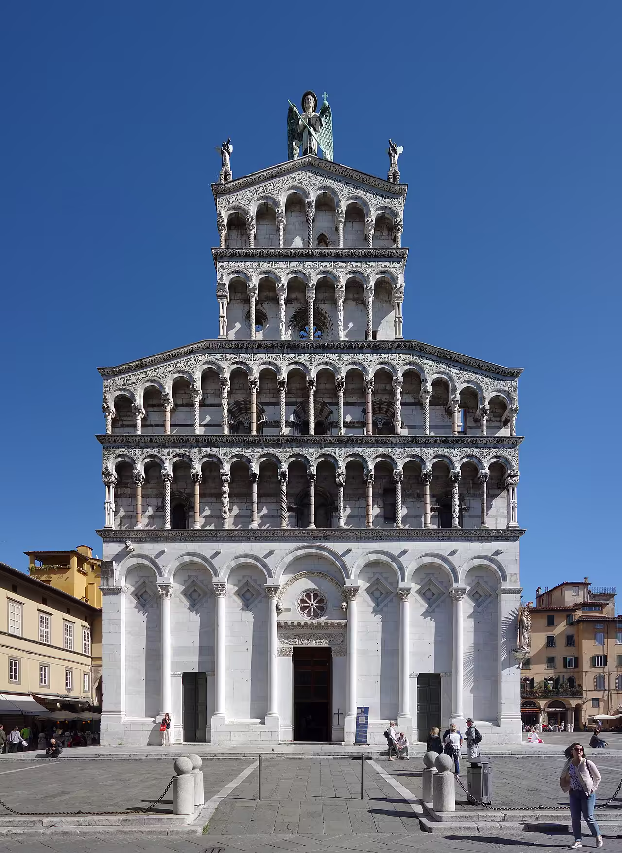 The tiered marble facade of San Michele in Foro, topped by a statue of the Archangel Michael